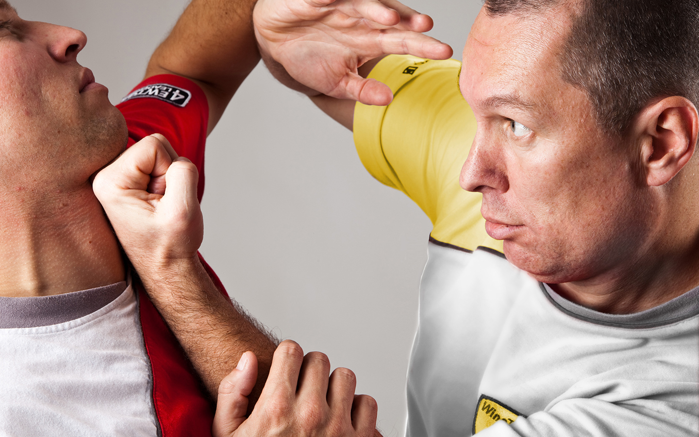 Grandmaster Prof. Dr. Oliver König in a fighting stance, delivering a punch to another man's chin with a clenched fist.